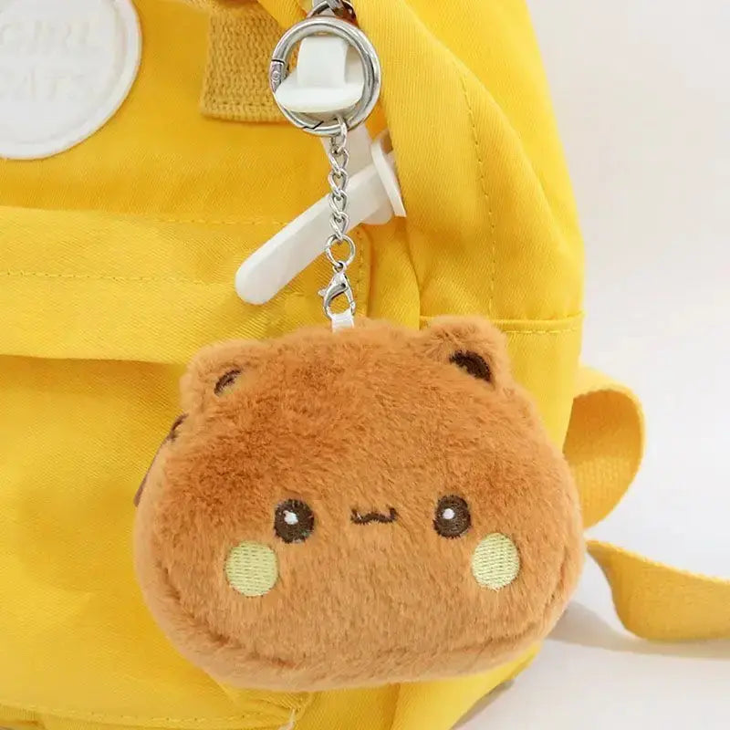 Cute Dudu and Bubu coin wallet keychain in plush design, attached to a yellow backpack.